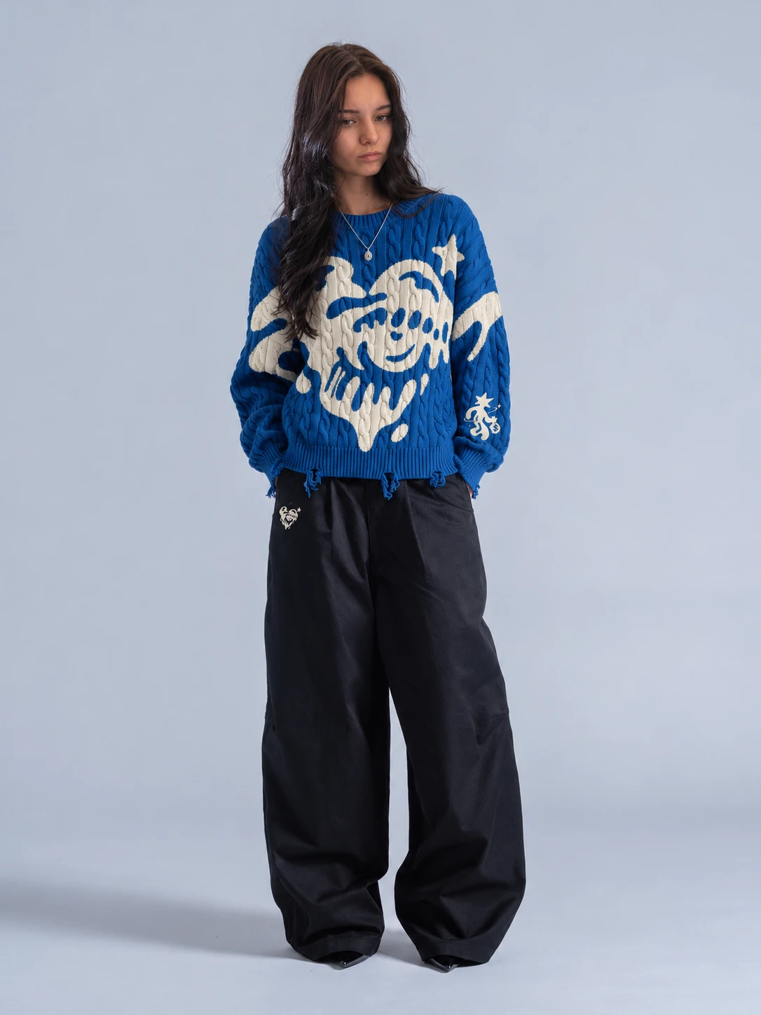 A cobalt cable knit with the cream melting heart across the front, worn with wide black trousers.